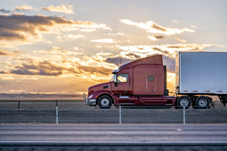 Red semi truck driving at sunset